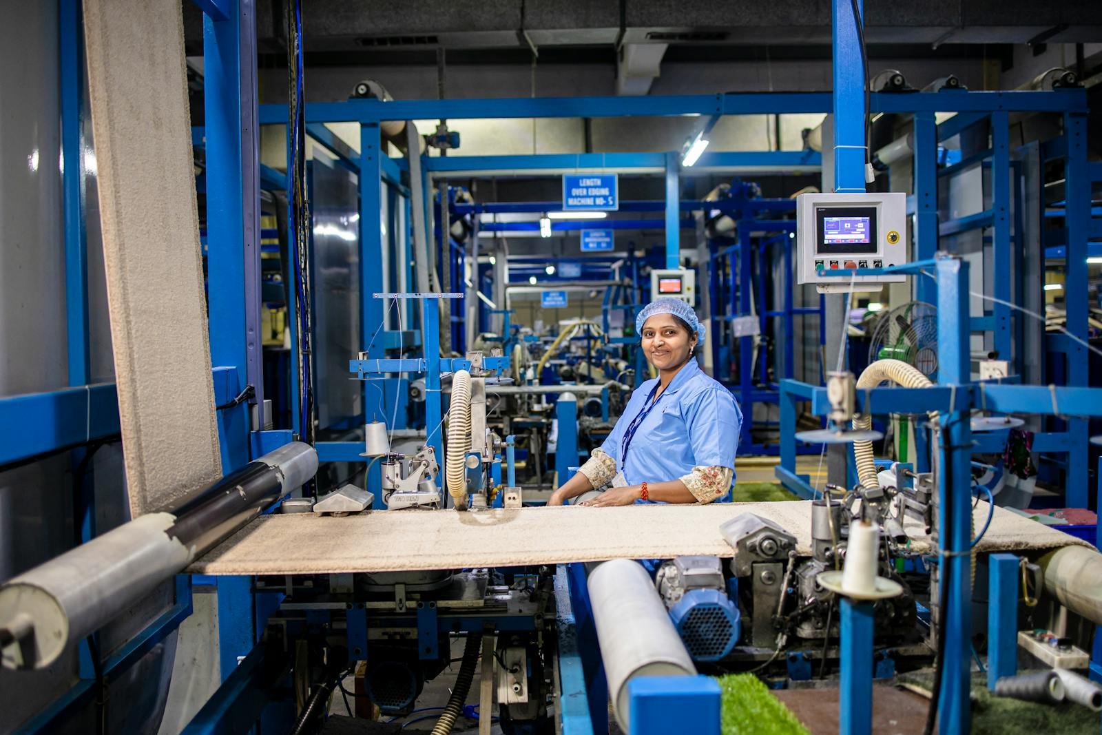 Portrait of an Indian female worker in a textile factory, showcasing industrial machinery.