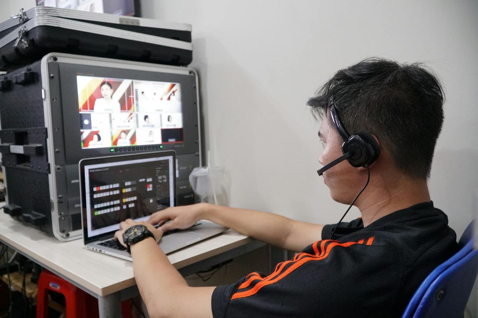 Technician manages multiple video feeds using laptop and monitor in studio setting.